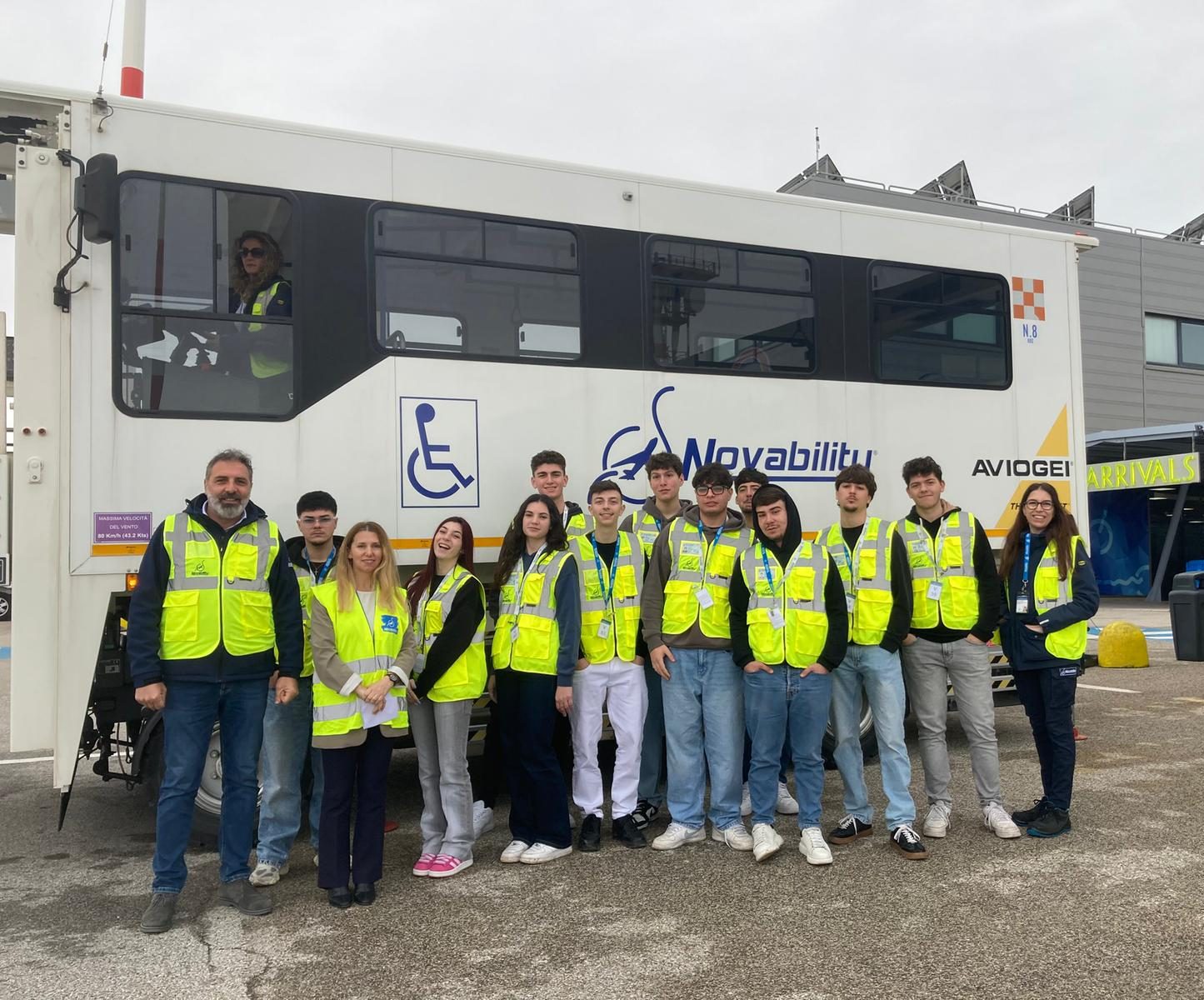 Ragazzi ed esperti davanti a un ambulift presso l'aeroporto di Brindisi.